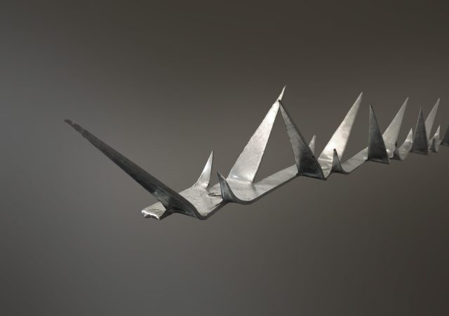 A close-up of a complex, angular origami model resembling a twisting, sharp-edged structure. Crafted from a single sheet of metallic paper, it reflects light to highlight its intricate geometric patterns against a gradient gray background that evokes the sleek, modern design of clearview fencing.